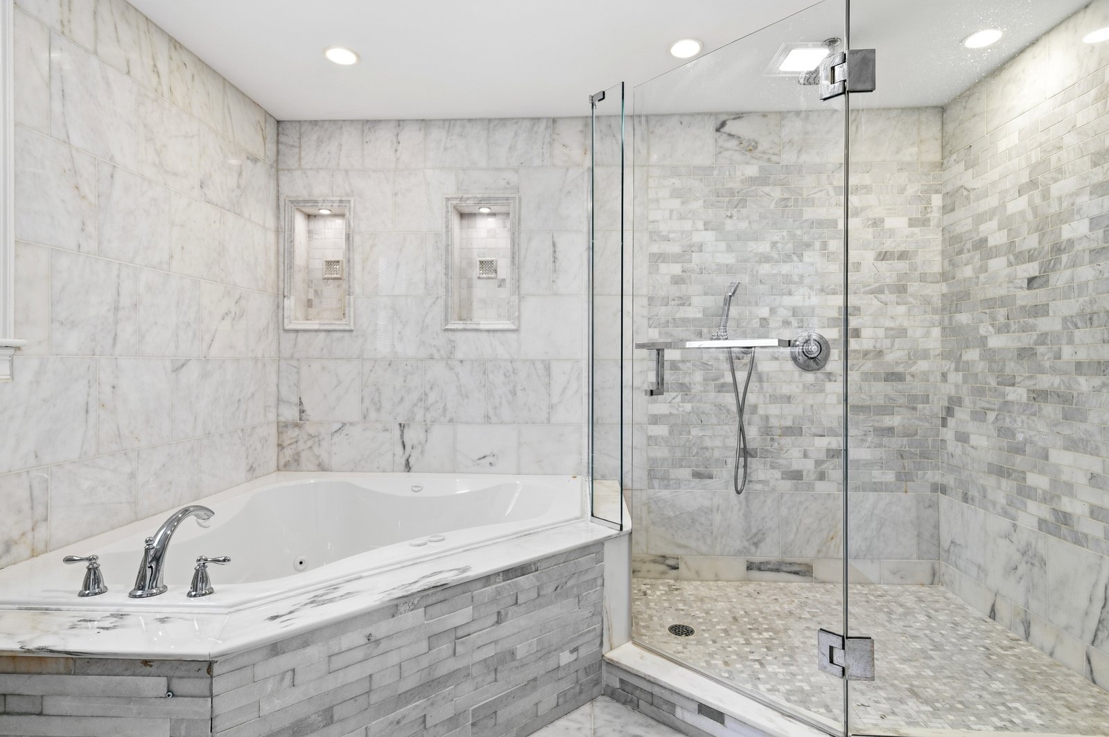 Primary en-suite bathroom with Jacuzzi tub, marble flooring, and double vanity